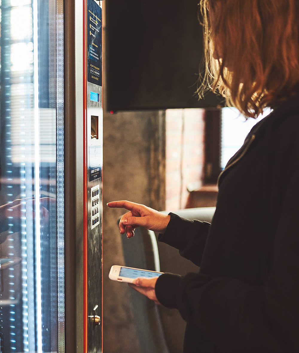 mujer pagando por producto en maquina expendedora